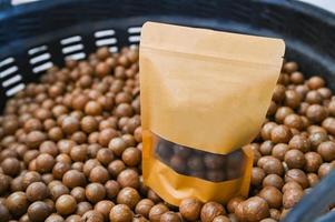 Nueces de macadamia en la cesta, nueces de macadamia frescas naturales sin cáscara crudas en un marco completo, cerrar la pila de nuez de macadamia tostada en el producto del paquete de bolsa foto