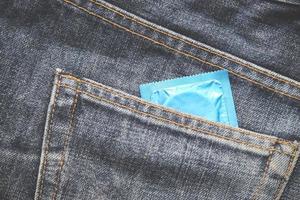 paquete de condones en jeans coloridos de condón en jeans azules de bolsillo en el fondo foto