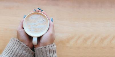 vista superior café caramelo mujer café con la mano sosteniendo una taza en la mesa de madera, taza de café caramelo en la mañana - macchiato de caramelo caliente foto