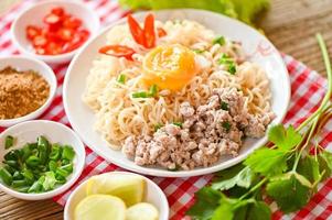 noodles plate with egg minced pork vegetable spring onion lemon lime lettuce celery and chili on table food , instant noodles cooking tasty eating with bowl noodle soup photo