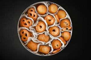 caja de galletas con galletas de mantequilla danesa sobre fondo de mesa negra, vista superior foto