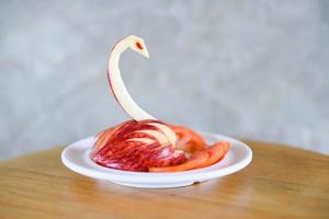 manzana tallada que sea un pájaro o un cisne en un plato blanco - tallado de frutas foto