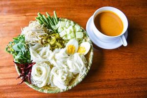 Thai rice noodles - Close up Thailand food vermicelli noodle boiled eggs and fresh vegetables on plate with curry soup bowl served wooden table photo