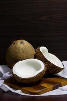 Tropical fruit concept, Halves of fresh coconuts and coconut on wooden saucer with white fabric