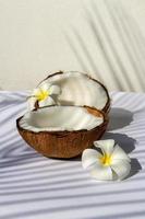 concepto de fruta tropical, mitades de coco blanco fresco y flor de plumeria sobre fondo de tela blanca