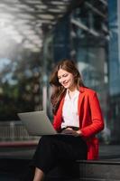 Young businesswoman using a Laptop, tablet on a bench in the city photo