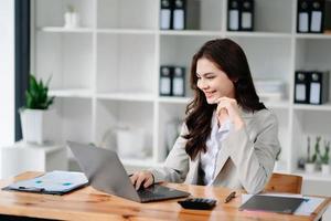 Asian female university student concentrating on her online classroom with tablet and laptop photo