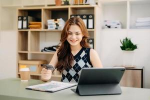 Woman using smart phone for mobile payments online shopping,omni channel,sitting on table,virtual icons graphics interface screen in morning light photo