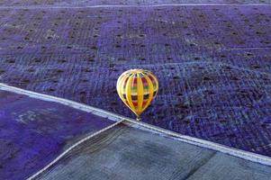 volando en un globo aerostático amarillo sobre campos de lavanda dando un marcado contraste de color y textura. foto