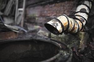 an old rusty downpipe near an abandoned house photo