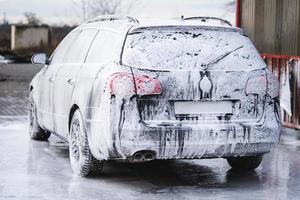 the car at the car wash is covered with foam, wash under pressure with a stream of water photo