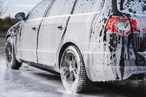 the car at the car wash is covered with foam, wash under pressure with a stream of water photo