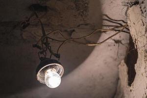 an old light bulb hangs on a wire in the basement photo