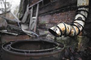un viejo bajante oxidado cerca de una casa abandonada foto