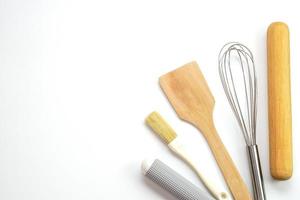 Top view kitchenware wooden rolling pin, wooden spatula and egg beater on white background. Materials or kitchen equipment for bakery. photo
