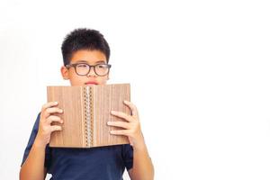 Young asian boy sitting cross-legged, holding a book. Education and learning concept. photo