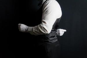 mayordomo de retrato de perfil o camarero con chaleco negro y guantes blancos de pie en elegante atención. a su servicio.