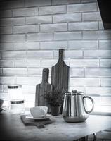 A still life with a teapot, cup, cutting boards, and some jars in black and white photo