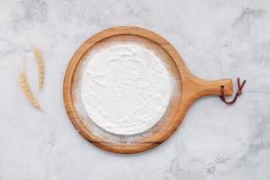 Pizza dough in wooden pizza platter set up on white concrete. Pizza tray on white concrete background flat lay and copy space. photo