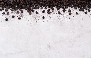 Dark roasted coffee beans setup on white concrete background with copy space. photo