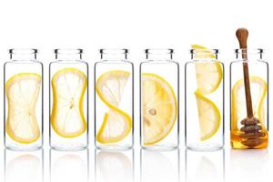 rodaja de limón casera para el cuidado de la piel y giro de limón en botellas de vidrio aisladas sobre fondo blanco.