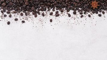 Dark roasted coffee beans setup on white concrete background with copy space. photo