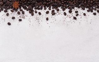 Dark roasted coffee beans setup on white concrete background with copy space. photo