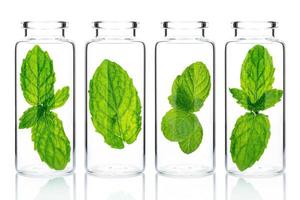 Bottles of essential oil with mint isolated on white background. photo