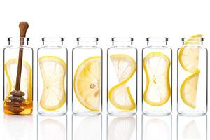 Homemade skin care lemon slice and lemon twist in glass bottles isolated on white background. photo