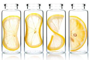 Homemade skin care lemon slice and lemon twist in glass bottles isolated on white background. photo