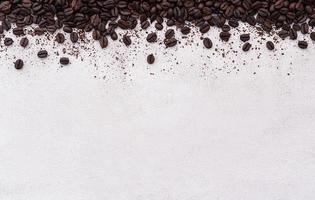 Dark roasted coffee beans setup on white concrete background with copy space. photo