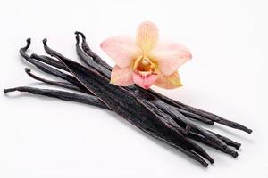 Dried vanilla sticks and orchid flower set up on marble background. photo