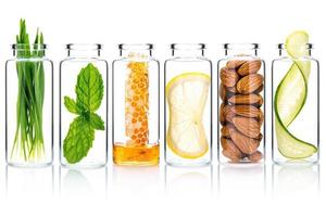 Homemade skin care with natural ingredients wheat glass ,cucumber slice ,almonds ,honeycomb ,lemon slice and mint leaves in glass bottles isolate on white background. photo