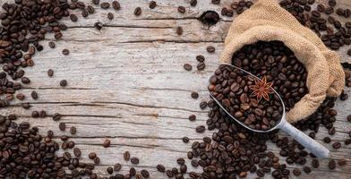 Background of dark roasted coffee beans with scoops setup on wooden background with copy space. photo