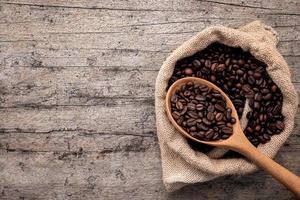 Background of dark roasted coffee beans with scoops setup on wooden background with copy space. photo