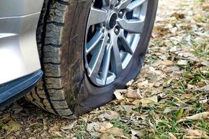 The tire broke because it was pierced by a solid object. The driver safely parked the car on the side of the road to call a mechanic to change the tire. Soft and selective focus. photo