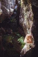 beautiful blonde girl in a white dress with a corset in a deep dark cave photo