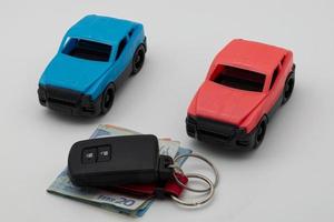 Red and blue car isolated on white background, car ignition key and euro banknotes. Insurance, traveling, transportation concept.