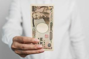 man hand holding Japanese Yen banknote stack. Thousand Yen money. Japan cash, Tax, Recession Economy, Inflation, Investment, finance and shopping payment concepts photo