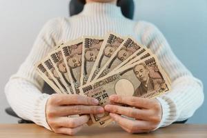 Woman hand counting Japanese Yen banknote over table background. Thousand Yen money. Japan cash, Tax, Recession Economy, Inflation, Investment, finance, savings, salary and payment concepts photo