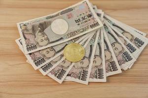 Japanese Yen banknote with gold Bitcoin cryptocurrency on table. BTC, Tax, Recession Economy, Inflation, Crypto, Investment and Decentralized Financial concepts photo