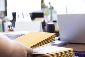 el enfoque suave del empleado de oficina o secretaria está preparando documentos y sobres marrones para aquellos interesados en licitar para la construcción de un gran edificio en una oficina. foto