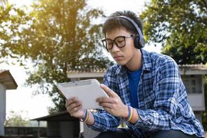 Portrait young asian boy wears rainbow wristband and listening to music on tablet in hand, concept for being assertive in presenting your true LGBT identity to today's society is accepted by society. photo