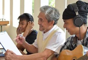 jóvenes asiáticos aprendiendo y tomando clases de música con un anciano maestro al lado del balcón de la sala de música, enfoque suave y selectivo en el primer niño, concepto para el disfrute de adultos y jóvenes. foto