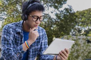 Portrait young asian boy wears rainbow wristband and listening to music on tablet in hand, concept for being assertive in presenting your true LGBT identity to today's society is accepted by society. photo