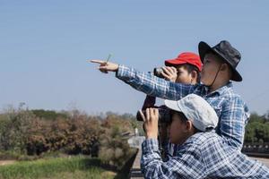 Asian boys are using binoculars to do the birds' watching in tropical forest during summer camp, idea for learning creatures and wildlife animals and insects outside the classroom. photo