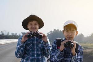 los niños asiáticos están usando binoculares para observar aves en el bosque tropical durante el campamento de verano, idea para aprender criaturas y animales salvajes e insectos fuera del aula. foto