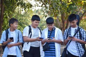 Soft focus young asian teens showing own mobile phones to their friends during walking back home after taking music class and doing school project work at school together. photo