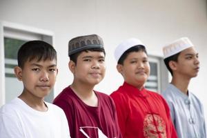 retrato de niños musulmanes o islámicos asiáticos sentados con niños musulmanes en fila para orar o hacer la actividad religiosa, enfoque suave y selectivo. foto