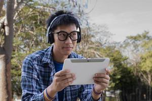 Portrait young asian boy wears rainbow wristband and listening to music on tablet in hand, concept for being assertive in presenting your true LGBT identity to today's society is accepted by society. photo